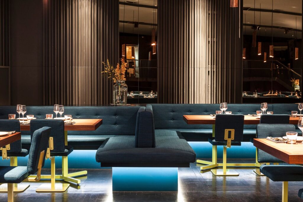 Modern restaurant with stylish interior, dark blue upholstered benches and subdued lighting, an exclusive choice for celebrating a birthday in Berlin.