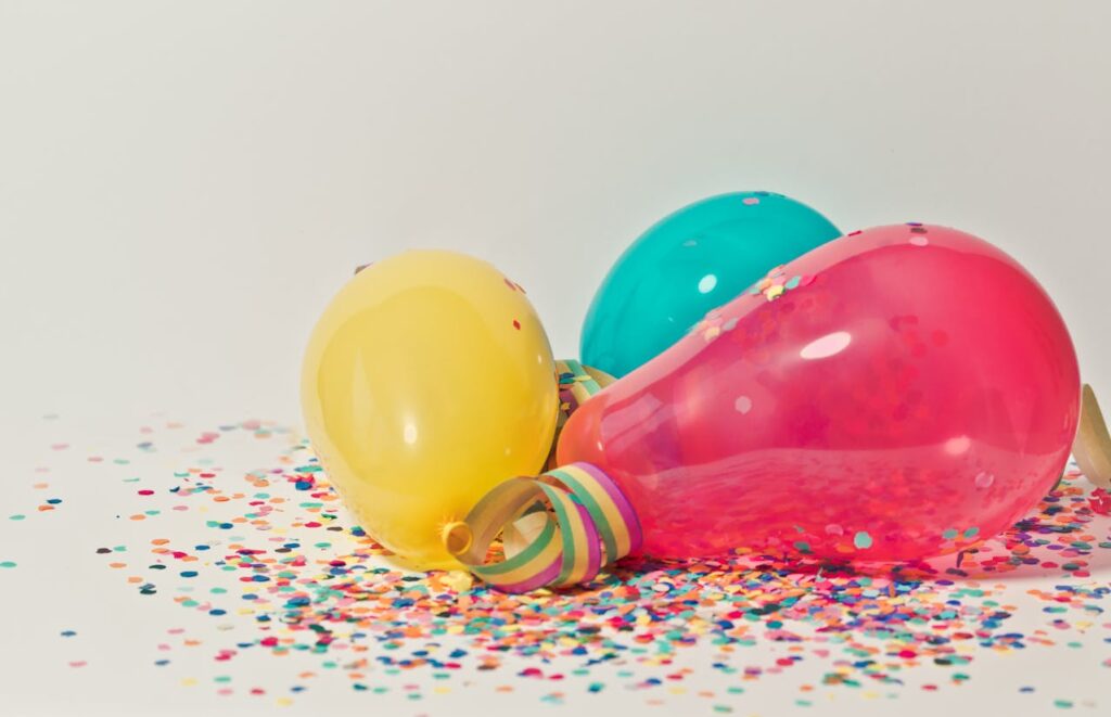 Colourful balloons and confetti on a white surface, creating a festive mood.