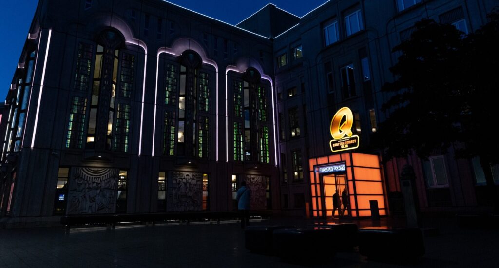 Nächtliches Ambiente mit warm beleuchtetem Eingangsbereich des Quatsch Comedy Clubs in Berlin.