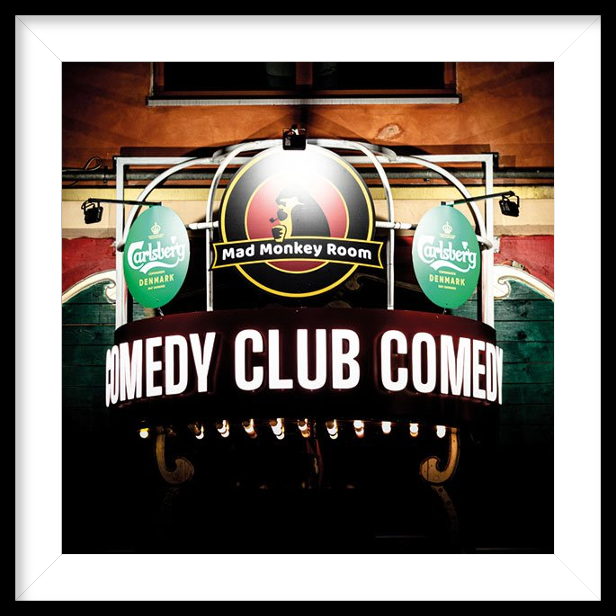 Außenaufnahme mit leuchtendem Werbeschild des Mad Monkey Room, eines beliebten Comedy-Clubs in Berlin.