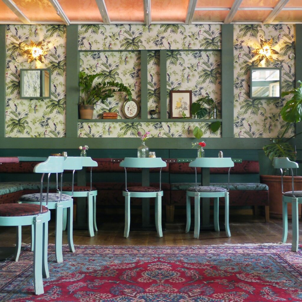 Playful decor with floral wallpaper and retro chairs at House of Small Wonder, one of Berlin's crazy restaurants.